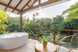 Een hottub op een houten terras, met uitzicht op weelderige begroeiing.