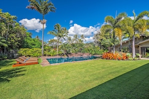 Un jardin bien entretenu avec une piscine, des palmiers et une pelouse.