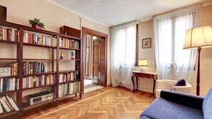 A living room with a sofa, a lamp, a table, and a bookshelf.