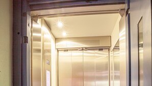 An elevator with metallic walls and a control panel on the left. - Hotel Monaco Zeebrugge Beach (Bruges)