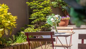 A wooden bench and table set outdoors with a potted plant and flowers on the table. - Hotel Monaco Zeebrugge Beach (Bruges)