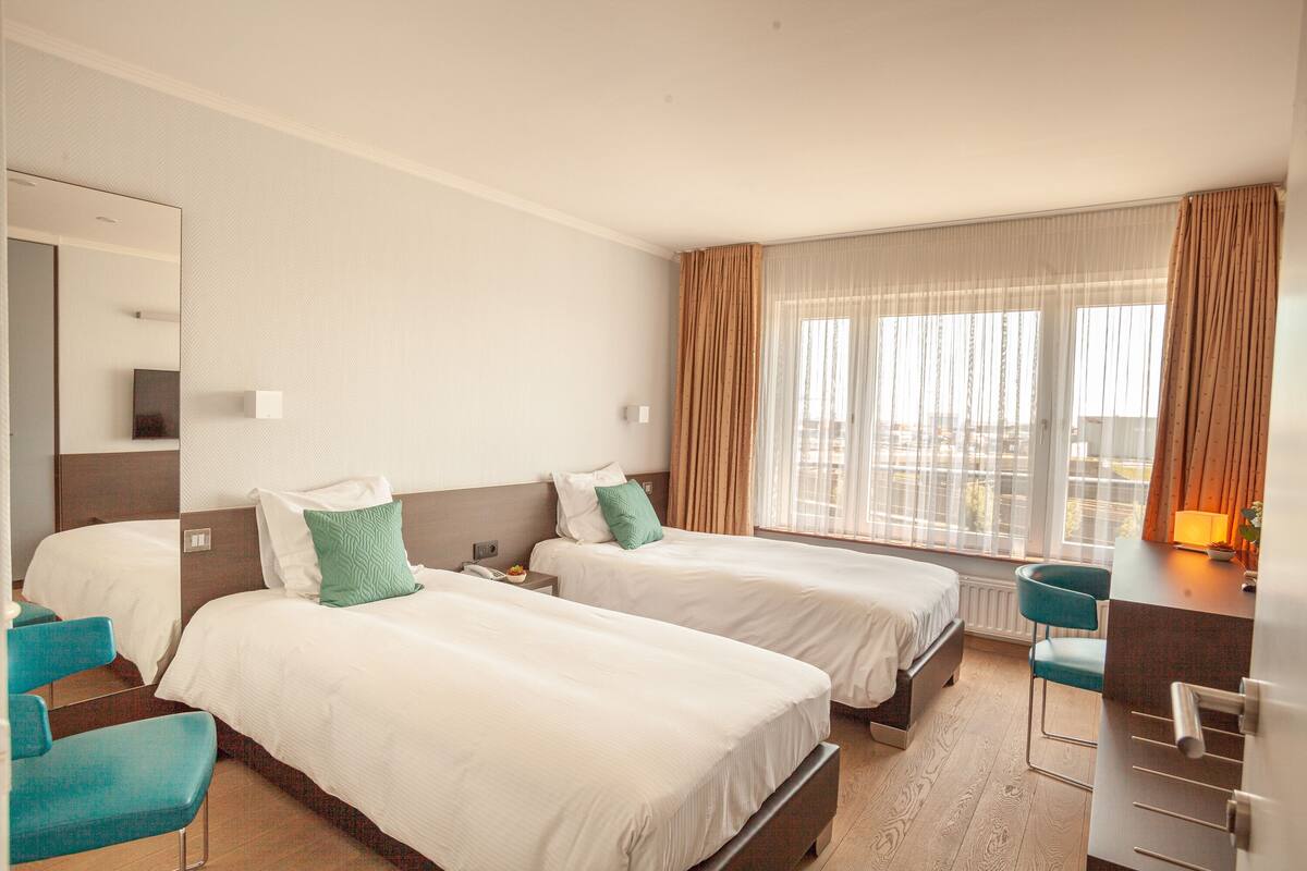 Une chambre d’hôtel avec deux lits, un bureau et une chaise.