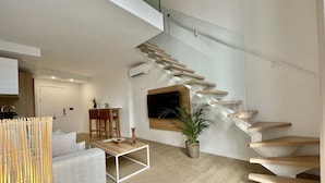 Un interior moderno con una escalera, una zona de comedor y un espacio de estar.