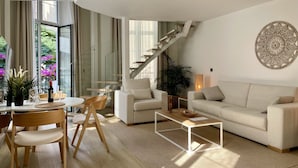 Una sala de estar moderna con una escalera, un comedor con mesa y sillas, y un sofá.