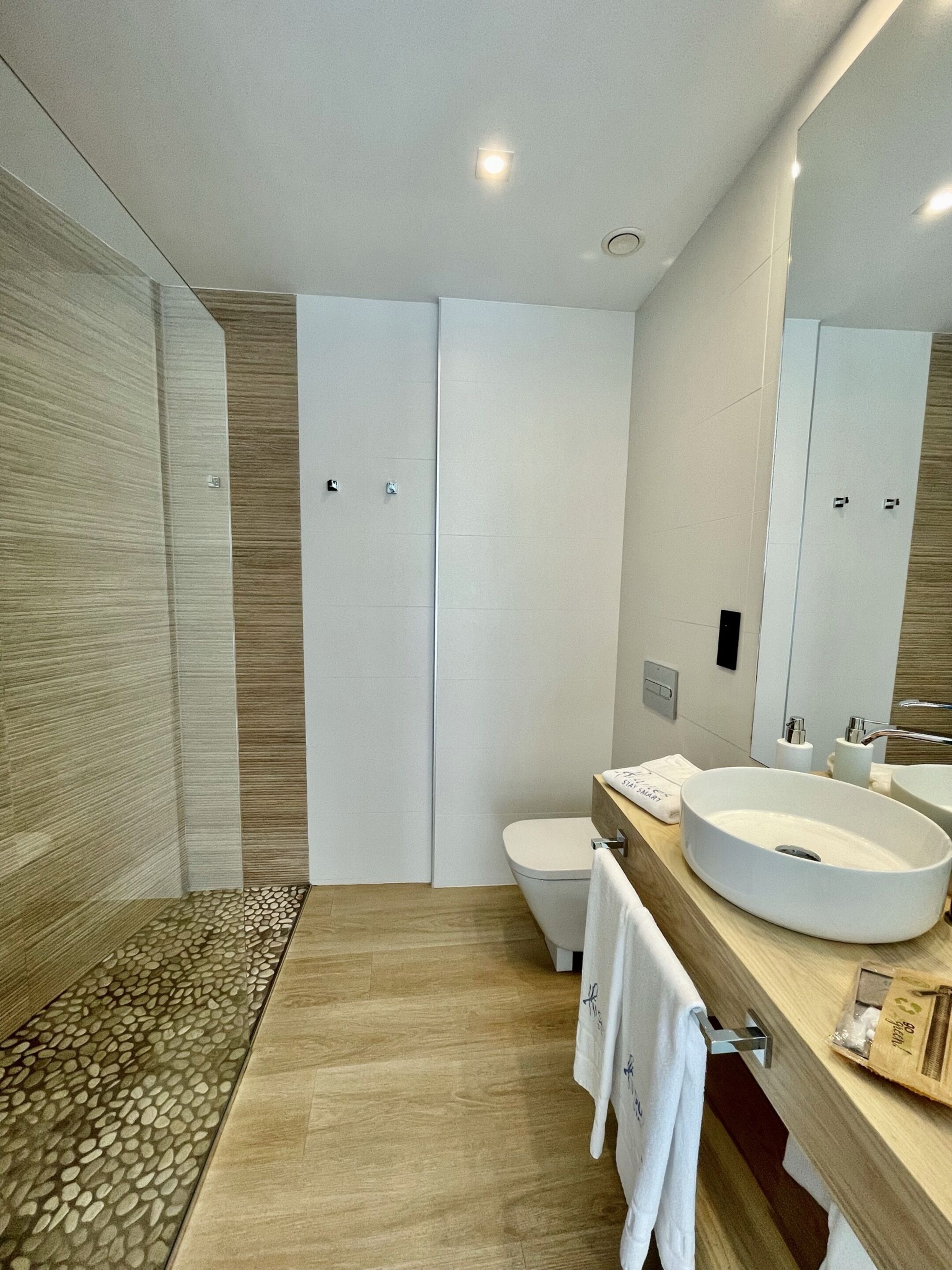 A modern bathroom with a large mirror, a round sink, and a toilet.