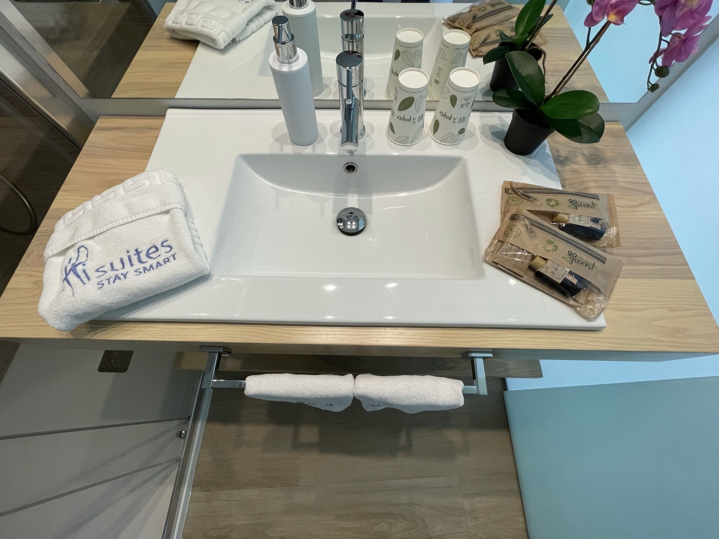 A bathroom with a white sink, a towel rack, and toiletries.