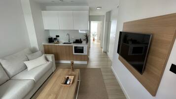 A modern living room with a sofa, coffee table, and a TV mounted on the wall.