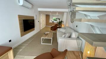 A modern living room with a sofa, a coffee table, and a TV mounted on the wall.