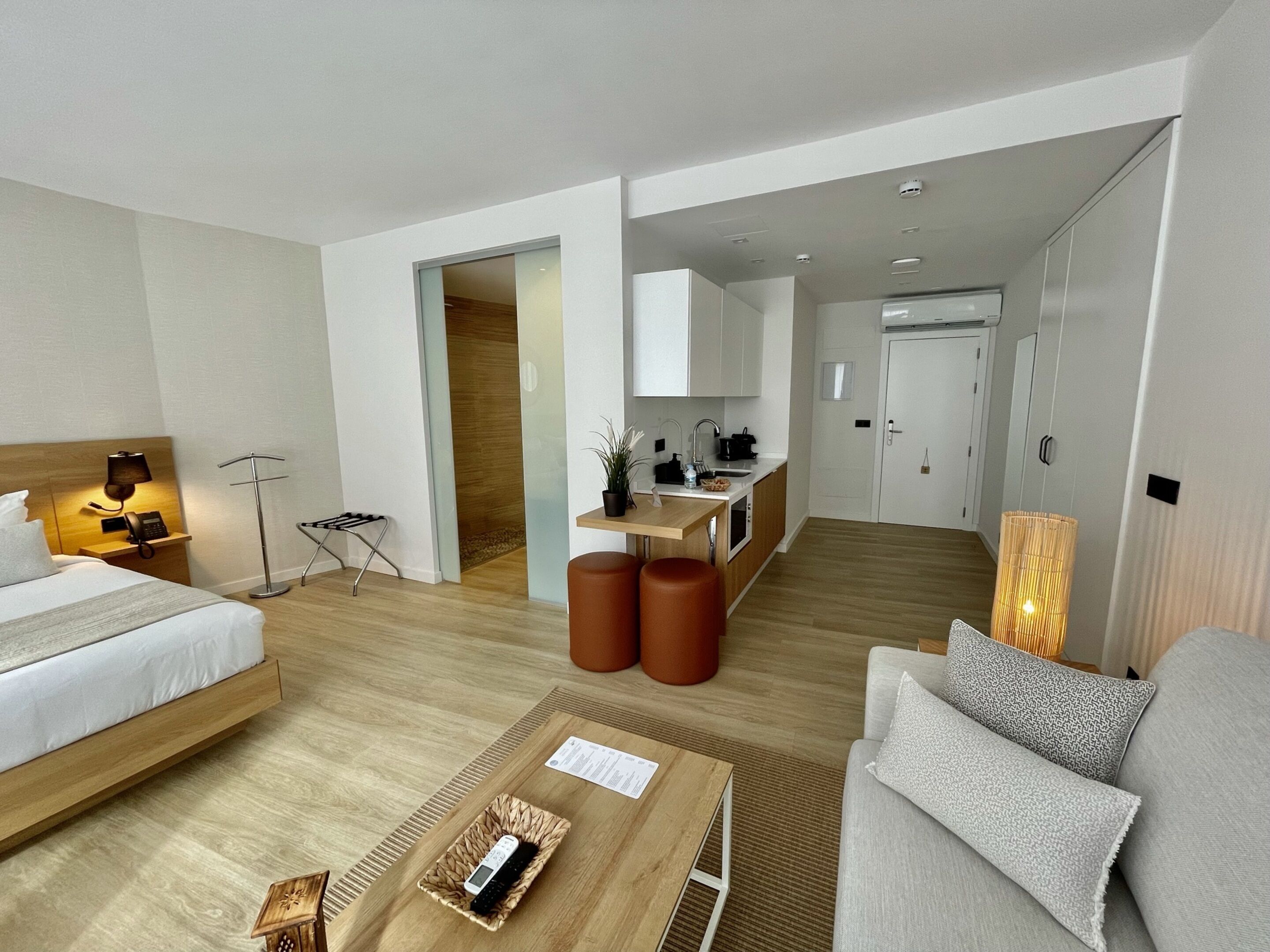 Ett modernt hotellrum med en säng, en soffa, en liten köksdel och ett matbord.