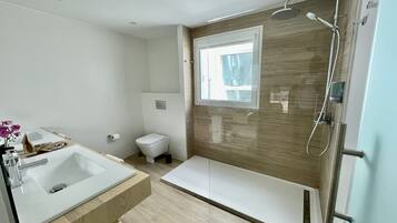 Un baño moderno con bañera, ducha, inodoro y lavamanos.