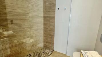 Bathroom features a vanity with a round mirror, a shower with a glass door, a toilet, and a storage cabinet.