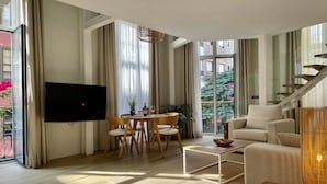 Una sala de estar moderna con un televisor de pantalla plana, un comedor con mesa y sillas, un sofá y una escalera.