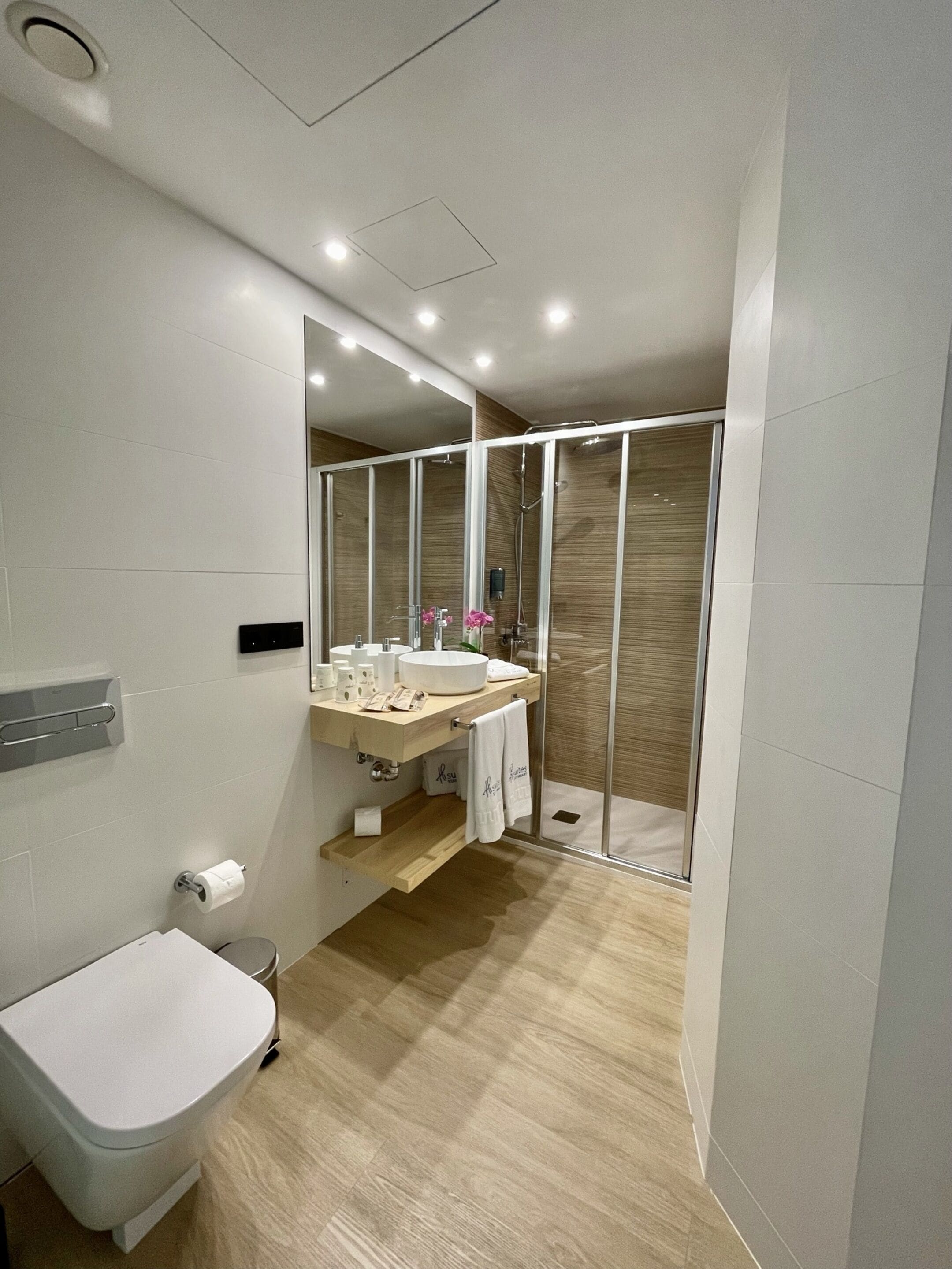 Un baño moderno con inodoro, lavamanos y zona de ducha.