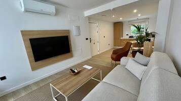 Una sala de estar moderna con un televisor de pantalla plana, una mesa de centro de madera y un sofá.