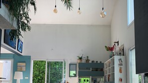 A spacious dining area with a table and chairs, a kitchen with cabinets and a refrigerator, and a large window providing natural light. - Architect's villa Lyon Collonges au mont d'or: Swimming pool, Nature, Bocuse, (Collonges-au-Mont-d'Or)