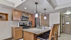 A modern kitchen with granite countertops, stainless steel appliances, and wooden cabinetry. - Canmore 2BR Condo, Near Banff (Dead Mans Flats)