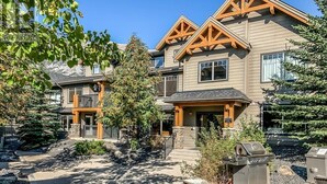 A multi-story building with a symmetrical facade, wooden trim, and a central entrance. - Canmore 2BR Condo, Near Banff (Dead Mans Flats)