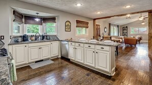 A spacious kitchen with white cabinetry, a large island, and wooden flooring.