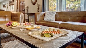 A wooden table with a cheese board, grapes, crackers, and vegetables.