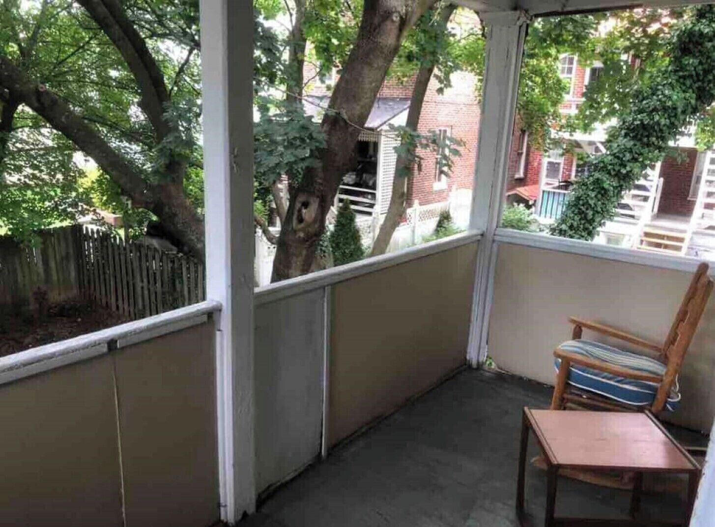 Un balcón pequeño con una silla de madera y una mesita.