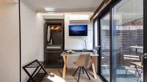A modern kitchen with a dining area, a TV mounted above the counter, and a sliding glass door leading to an outdoor patio. - Diagonal Amazing 3BD with private garden (Barcelona)