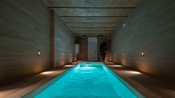 A swimming pool with a wooden interior, a door at the end, and wall-mounted lights. - Diagonal Amazing 3BD with private garden (Barcelona)