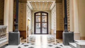 A grand hallway with a checkered marble floor, classical columns, and a large arched doorway. - Elegant and historic 3BD in Pl Urquinaona! (Barcelona)