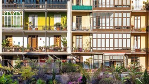 A multi-story building with balconies, large windows, and a variety of potted plants. - Elegant and historic 3BD in Pl Urquinaona! (Barcelona)