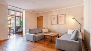 A living room with two grey sofas, a wooden coffee table, and a floor lamp. There is a door and two framed pictures on the wall. - Elegant and historic 3BD in Pl Urquinaona! (Barcelona)