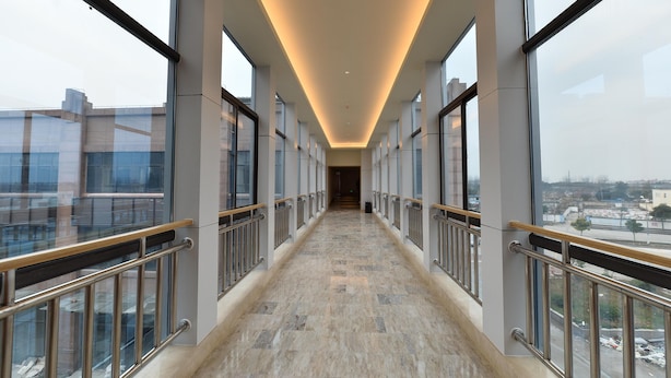 A corridor with glass railings, a tiled floor, and a view of the cityscape. - Ji Hotel (Shanghai)