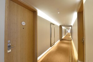 Un pasillo de hotel con puertas de madera, suelo alfombrado y un cartel que indica la habitación 6305.
