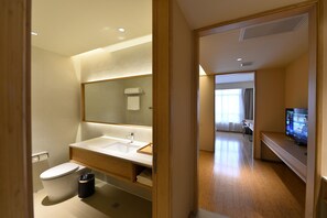 A modern bathroom with a large mirror, a toilet, and a sink.