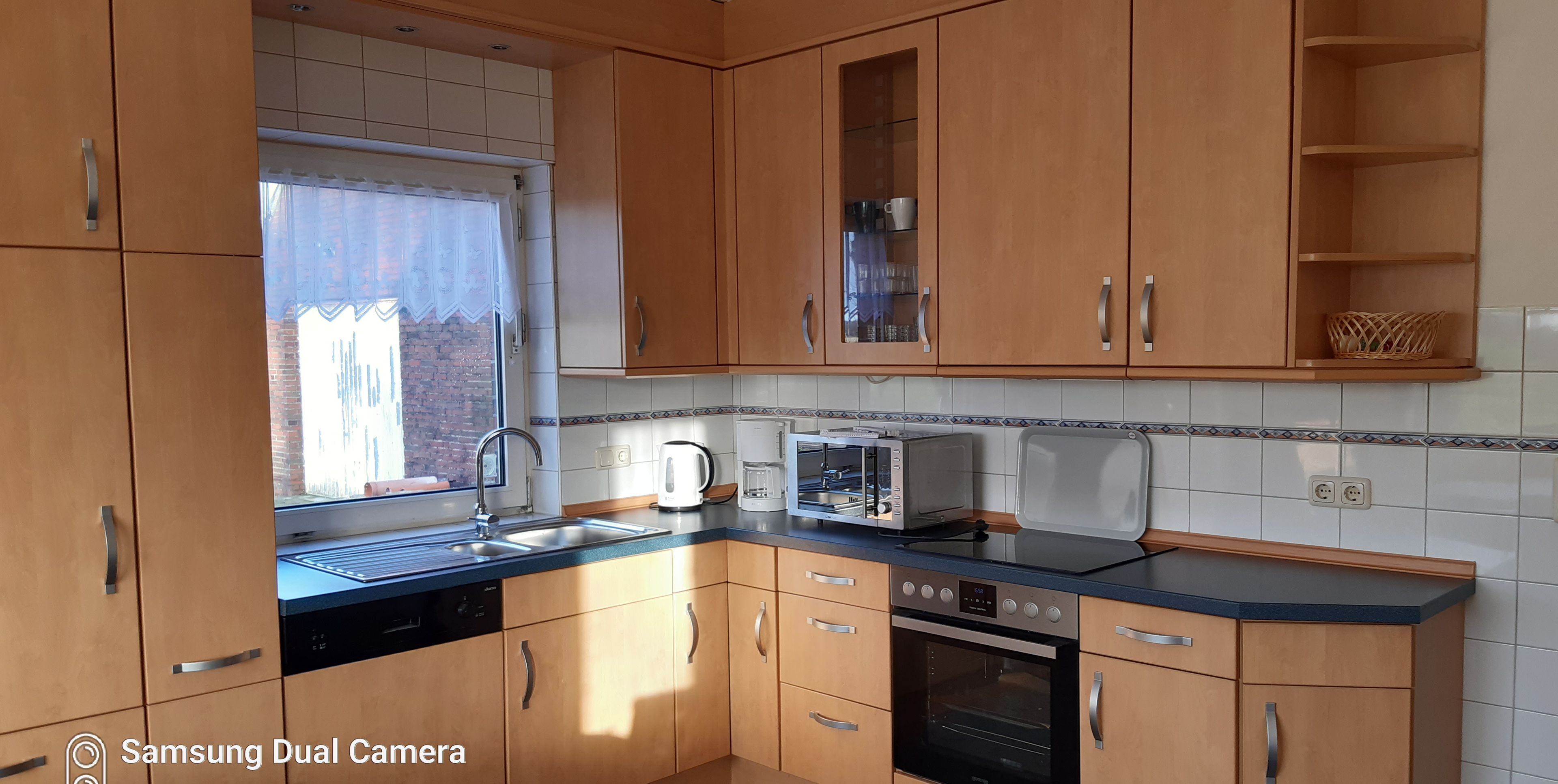 A modern kitchen with wooden cabinets, a built-in oven, a microwave, and a toaster.