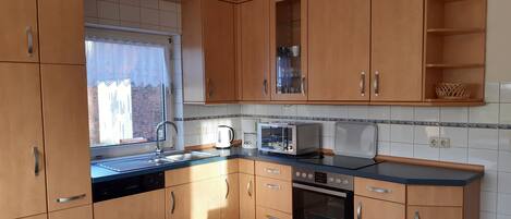 A modern kitchen with wooden cabinets, a built-in oven, a microwave, and a toaster.