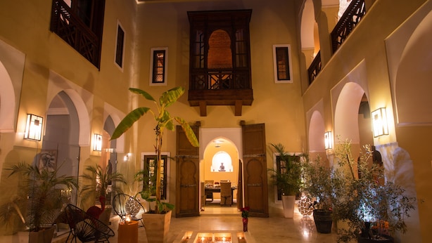 A spacious lobby with a central seating area, multiple potted plants, and a view of a dining area in the background. - RIAD HIZAD (Marrakech)