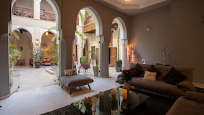 A spacious living area with a high ceiling, arched doorways, and a central seating area with a sofa and a coffee table. - RIAD HIZAD (Marrakech)