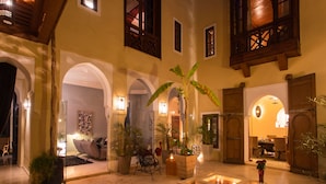 A spacious indoor courtyard with a seating area, potted plants, and a dining setup. - RIAD HIZAD (Marrakech)