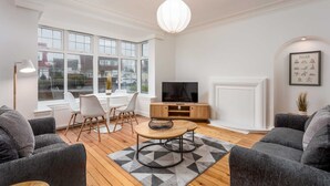 A modern living room with a TV, sofa, and dining area.