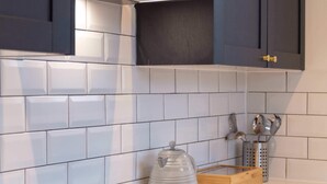 A modern kitchen with dark cabinets, white tiles, a black induction cooktop, and a stainless steel range hood.