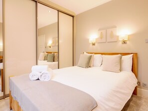 Une chambre d’hôtel avec un grand lit, un miroir et des lampes fixées au mur.