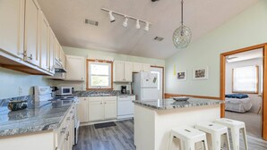 Een moderne keuken met witte kasten, granieten aanrecht en een centraal eiland met barkrukken.