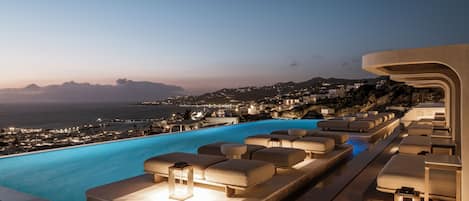 A poolside area with lounge chairs and a view of the coastline.