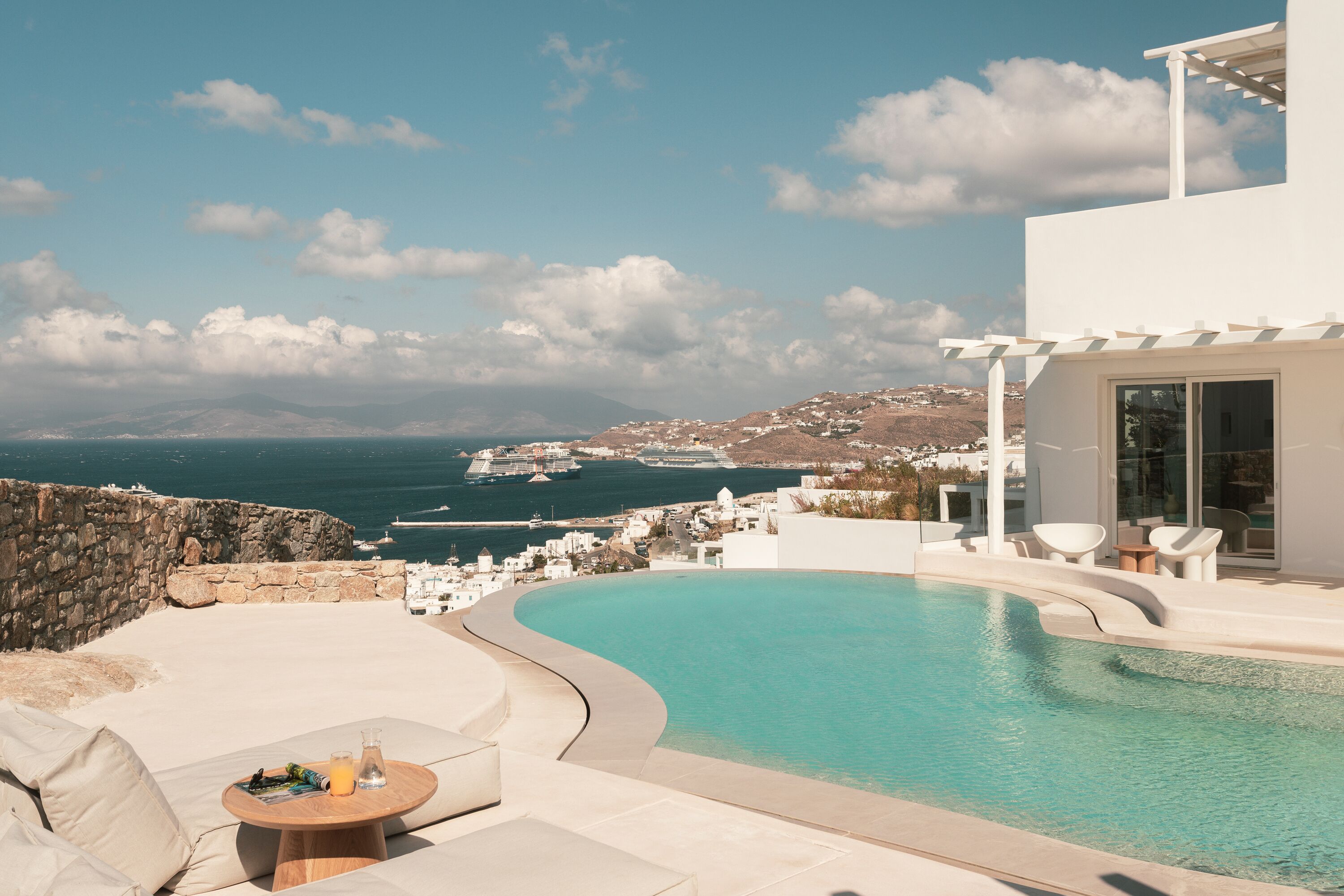 A modern pool area with a view of the sea and a distant coastline.