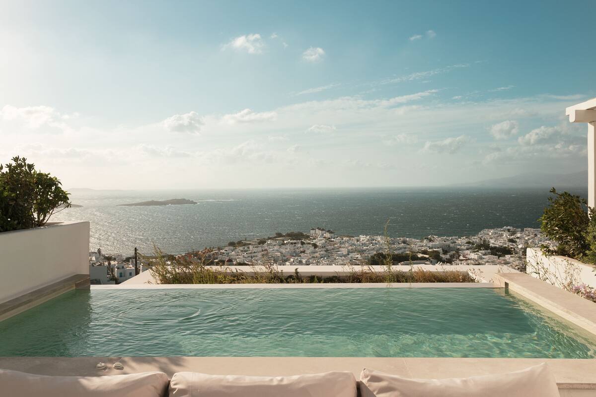 A pool with a view of the sea and a town.