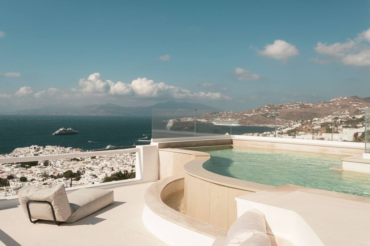 A rooftop pool with a view of a coastal town and the sea.