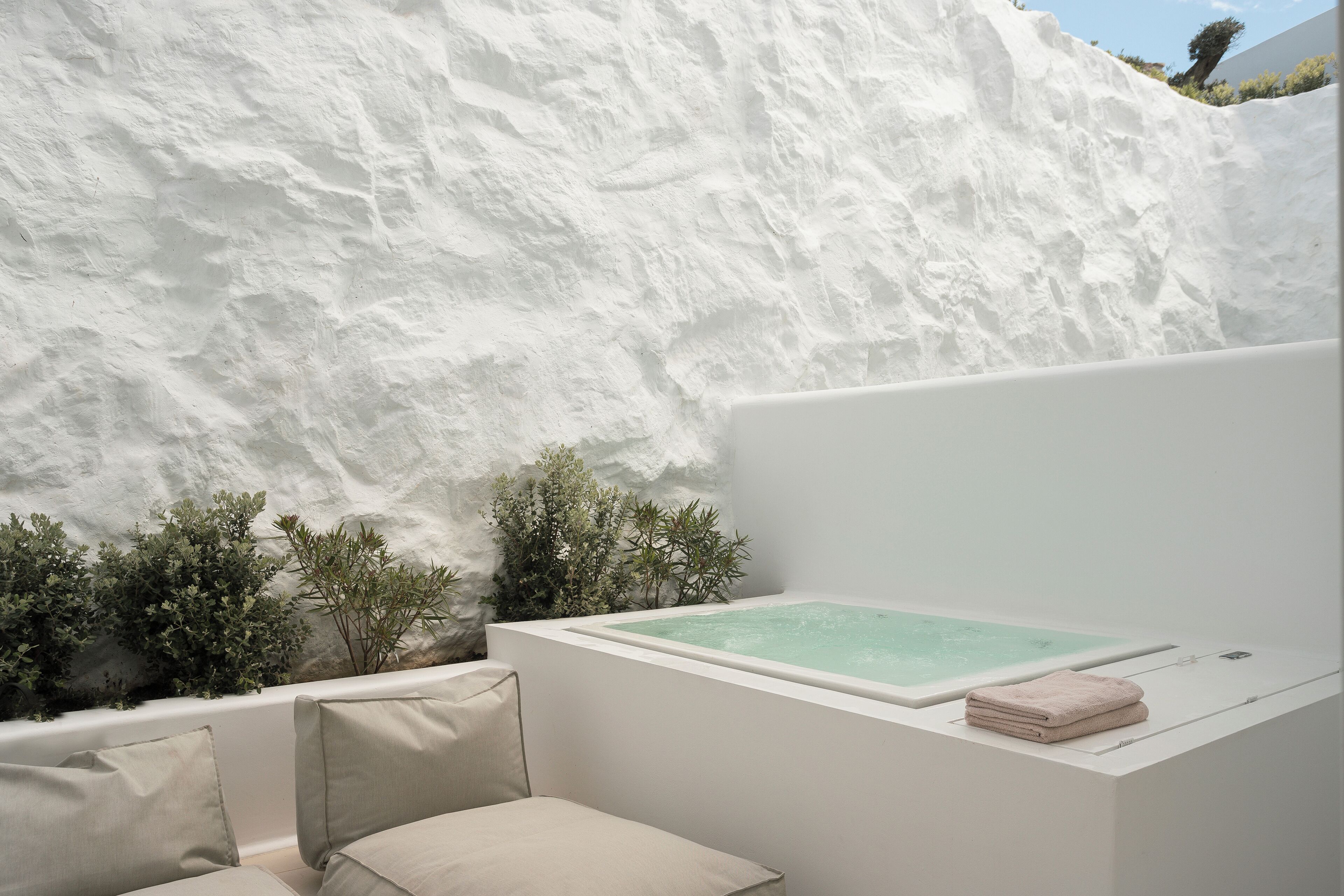 Un área de spa con bañera, banco y un pequeño jardín.