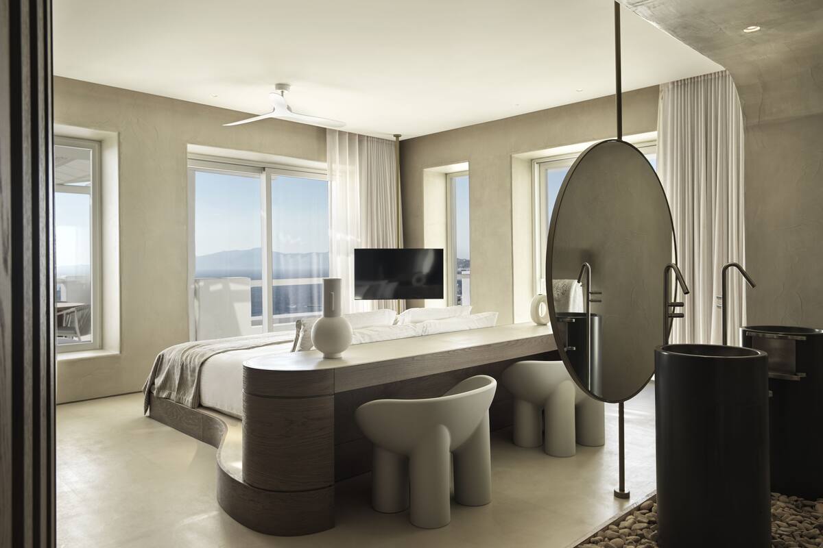 A modern bedroom with a curved bed, a TV, and a large mirror.