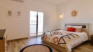 A bedroom with a bed, a dresser, a window, and a wall-mounted air conditioner.