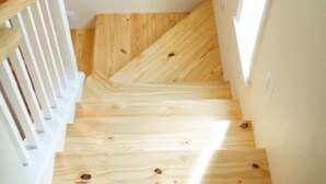 A wooden staircase with white railings, leading to a room with a window.