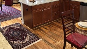 A modern kitchen with wooden cabinets, a built-in island, and a dining area with a red chair.